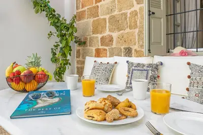 a table with a book and a plate of food at Amarada City Suites in Rhodes Town