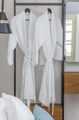 a rack of white robes hanging in a bedroom at Amarada City Suites in Rhodes Town