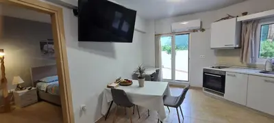 a kitchen with a table with chairs and a television on the wall at Annie's Apartment in Ialyssos
