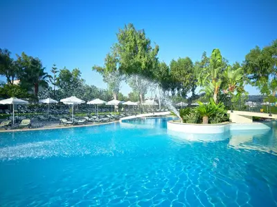 a large swimming pool with blue water and umbrellas at Atlantica Princess Hotel in Ixia