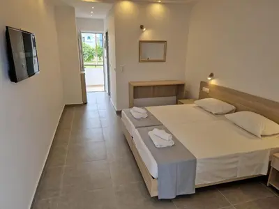 a hotel room with a bed and a television at Lilly Rooms in Faliraki