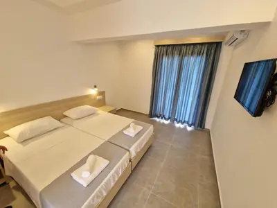 a bedroom with two beds and a flat screen tv at Lilly Rooms in Faliraki