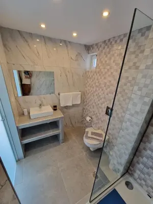 a bathroom with a shower and a toilet and a sink at Lilly Rooms in Faliraki