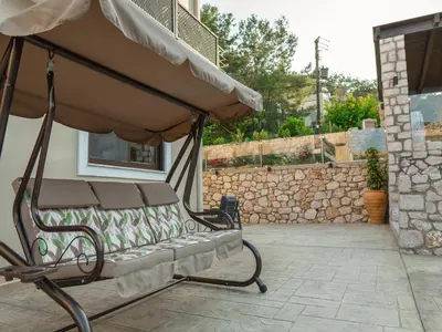 a bench with an umbrella on a patio at Adonis Villa in nature in Ixia