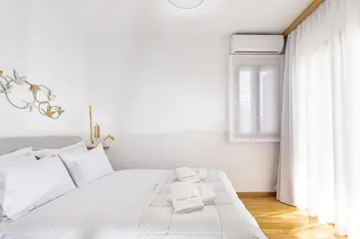 a white bedroom with a white bed and a window at Villa Dafni - Lindos in Líndos