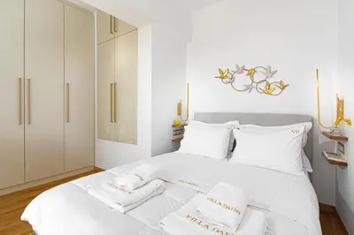 a white bedroom with a white bed with white pillows at Villa Dafni - Lindos in Líndos