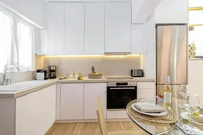 a kitchen with white cabinets and a glass table at Villa Dafni - Lindos in Líndos