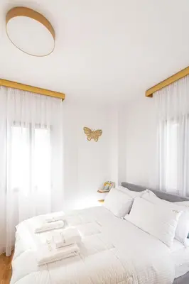 a white bedroom with a large white bed with white pillows at Villa Dafni - Lindos in Líndos
