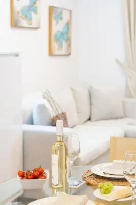 a table with a bottle of wine and a bowl of fruit at Villa Dafni - Lindos in Líndos