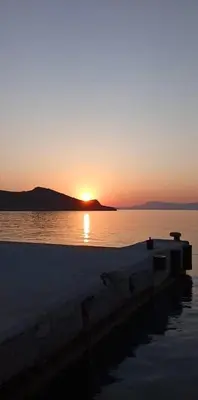 a sunset over a body of water with a boat at Occasus Room Comfort in Halki
