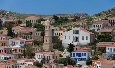 a village with a clock tower and houses at Occasus Room Comfort in Halki