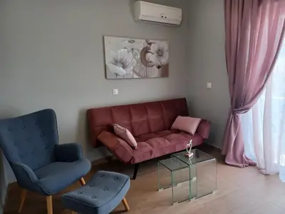 a living room with a red couch and two chairs at Melenia Suites in Rhodes Town