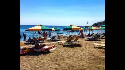 a beach with people sitting on chairs and umbrellas at Paradise Studios in Faliraki