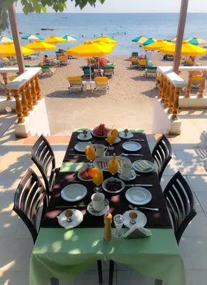 a table with food on the beach with chairs and umbrellas at Paradise Studios in Faliraki