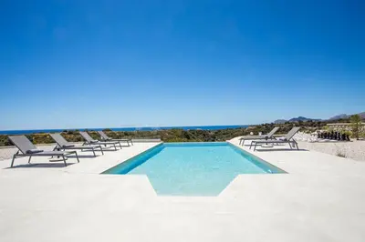 a swimming pool with lounge chairs and the ocean at Your House In Rhodes in Afantou