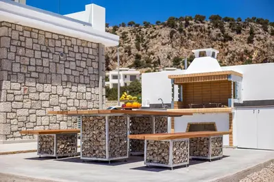 a outdoor kitchen with wooden tables and a stone wall at Your House In Rhodes in Afantou