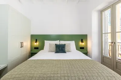 a bedroom with a large bed with a green headboard at Suite Christina in Symi