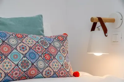 a pillow sitting on a bed next to a lamp at Suite Christina in Symi