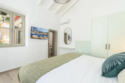 a white bedroom with a bed and a window at Suite Christina in Symi
