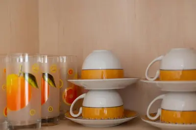 three cups and plates on a table with oranges at Tsampika's Beachfront House in Stegna in Archangelos