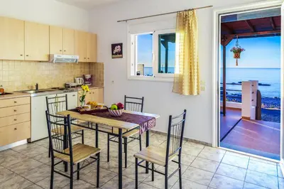 a kitchen with a table and chairs with a view of the ocean at Tsampika's Beachfront House in Stegna in Archangelos