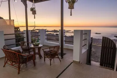 a balcony with a table and chairs and a view of the ocean at Tsampika's Beachfront House in Stegna in Archangelos