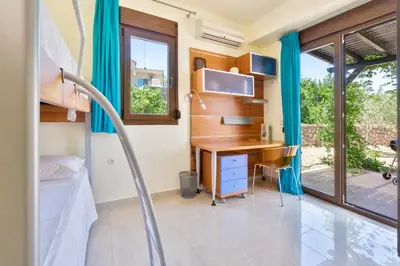 a room with a desk and a bed and a window at Smaragdi Beachfront Villa in Asklipiḯon