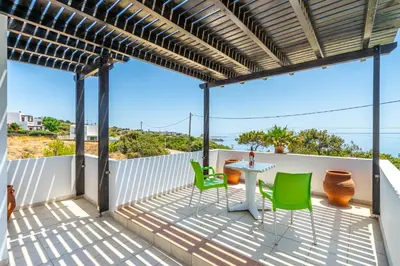 a patio with a table and green chairs at Smaragdi Beachfront Villa in Asklipiḯon