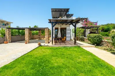 a backyard with a pergola and green grass at Smaragdi Beachfront Villa in Asklipiḯon