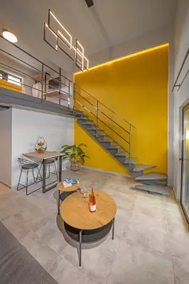 a room with a yellow wall and tables and a staircase at Amarada Marina Suites in Rhodes Town