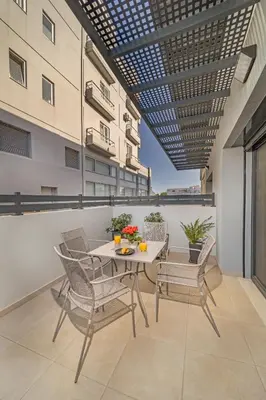 a patio with a table and chairs on a balcony at Amarada Marina Suites in Rhodes Town