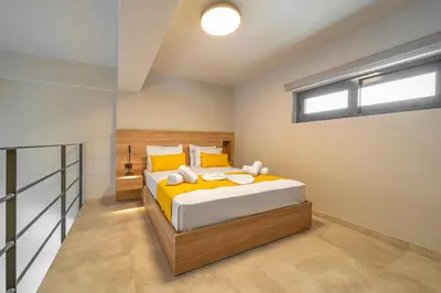 a bedroom with a bed with yellow sheets and a window at Amarada Marina Suites in Rhodes Town