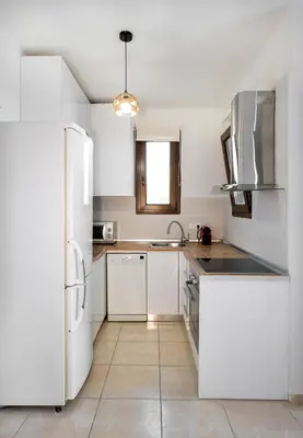 a kitchen with white cabinets and a refrigerator at Memi Beach front Villa in Kiotari