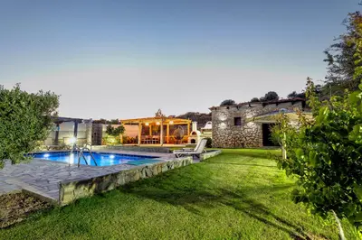 a backyard with a swimming pool and a house at Memi Beach front Villa in Kiotari