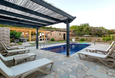 a patio with chairs and a swimming pool at Memi Beach front Villa in Kiotari