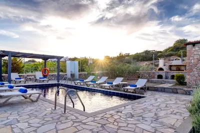 a pool with chaise lounge chairs and a resort at Memi Beach front Villa in Kiotari