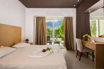 a hotel room with a bed and a desk with a flower on it at Anavadia Hotel-All Inclusive in Kolimbia