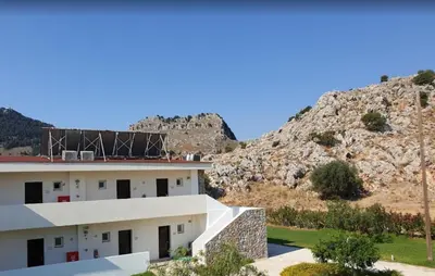a building with a mountain in the background at Anavadia Hotel-All Inclusive in Kolimbia
