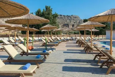 a row of lounge chairs and umbrellas next to a pool at Anavadia Hotel-All Inclusive in Kolimbia