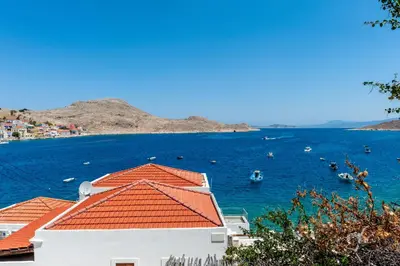 a building with an orange roof next to a body of water at Kiki&Nina in Halki