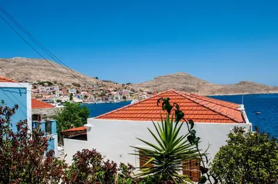 a white building with a red roof next to the water at Kiki&Nina in Halki