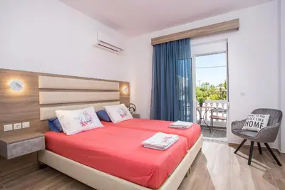a bedroom with a large bed with a red blanket at Dimitra Faliraki Center Apartments in Faliraki