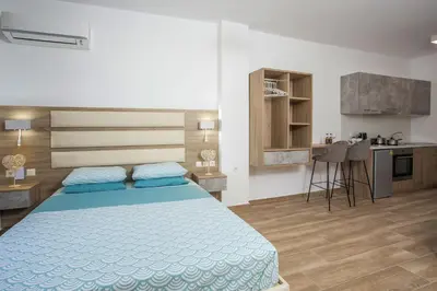 a bedroom with a blue bed and a kitchen at Dimitra Faliraki Center Apartments in Faliraki