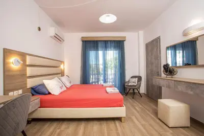 a bedroom with a large bed with a red blanket at Dimitra Faliraki Center Apartments in Faliraki
