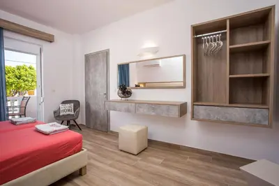 a bedroom with a red bed and a mirror at Dimitra Faliraki Center Apartments in Faliraki