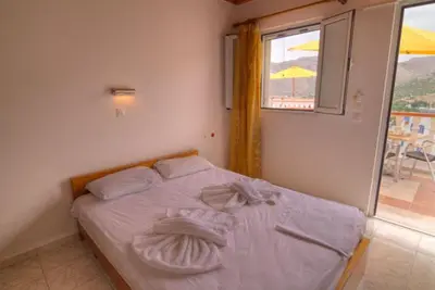 a bedroom with a bed with white sheets and a window at Seva' s Studios in Livadia
