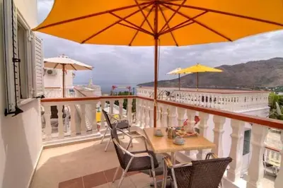 a balcony with a table and chairs and an umbrella at Seva' s Studios in Livadia