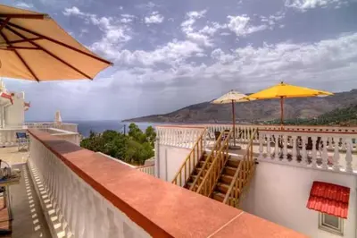 a balcony with tables and chairs and umbrellas at Seva' s Studios in Livadia