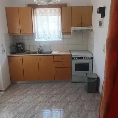 a kitchen with wooden cabinets and a sink and a stove at Seva' s Studios in Livadia