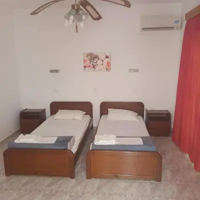 two twin beds in a room with a ceiling fan at Seva' s Studios in Livadia